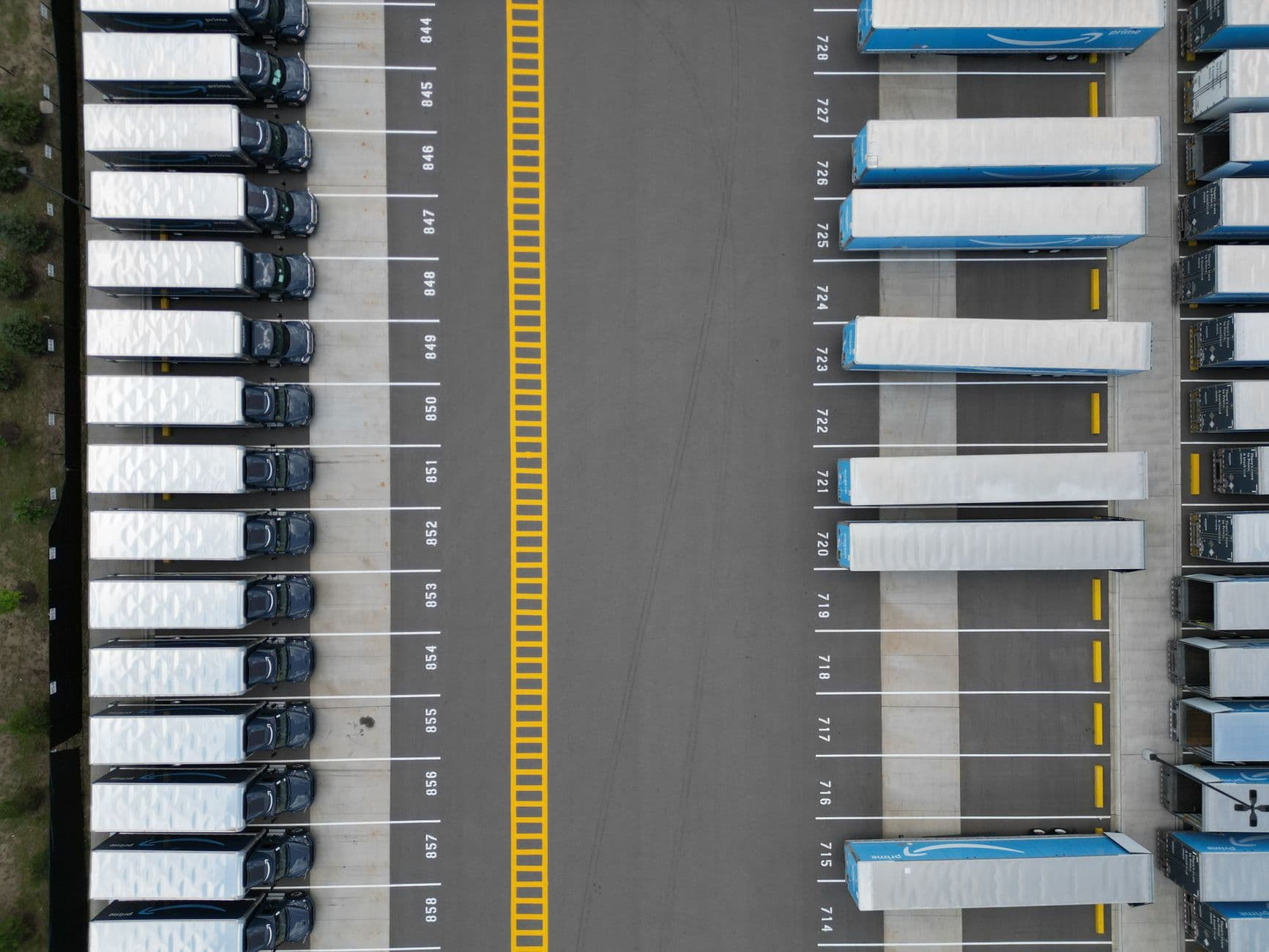Top-down view of lined-up trucks at a logistics parking lot, showing organized transportation hub.